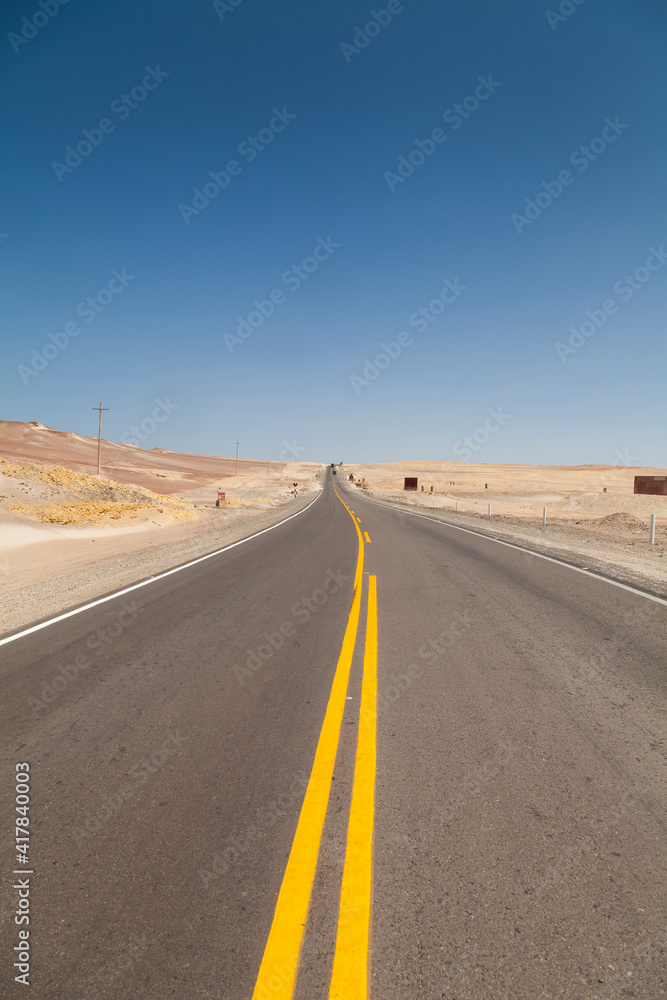 Naklejka premium Yellow lines painted in a road, a lonely, desert and scorching place, in the Paracas Peninsula, near Ica, on the road to Pisco, in Peru, South America.