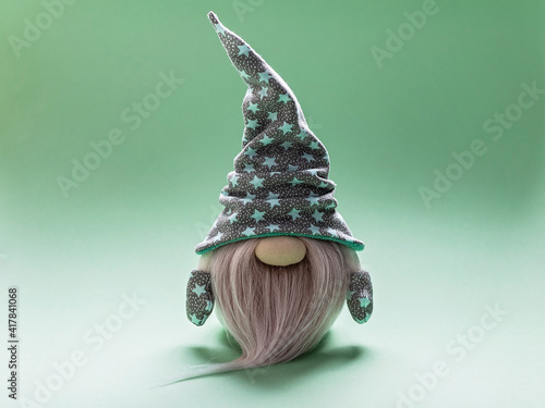 Cute bearded gnome in a cap with stars on a light green background. Handmade soft toy. Home decor photo