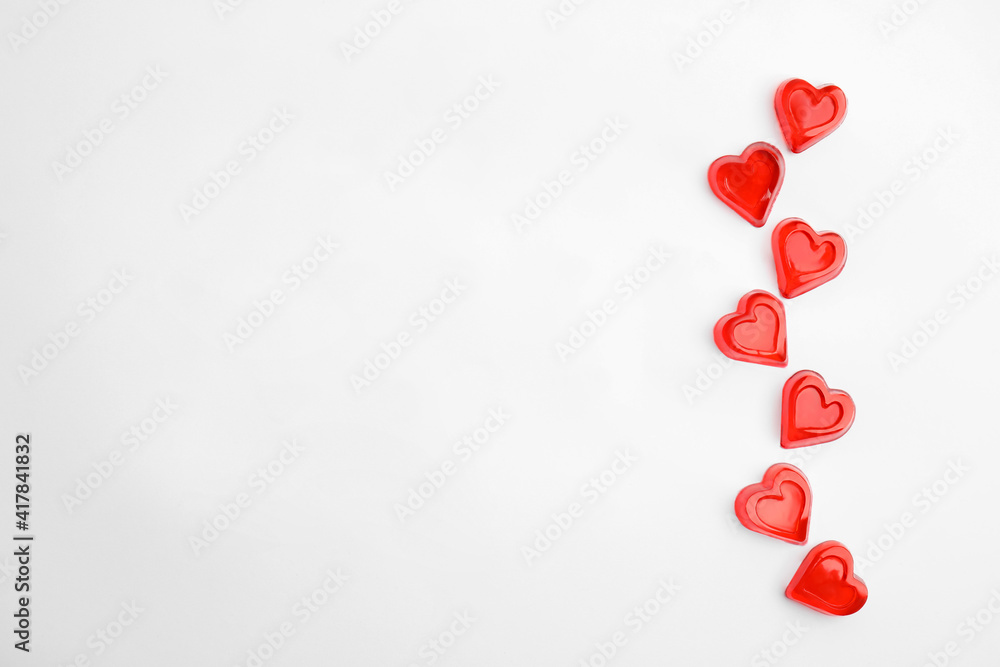 Sweet heart shaped jelly candies on white background, flat lay. Space for text