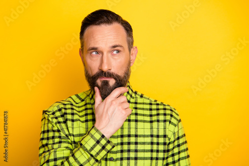 Portrait of attractive minded man touching chin thinking wearing checked shirt isolated over bright yellow color background