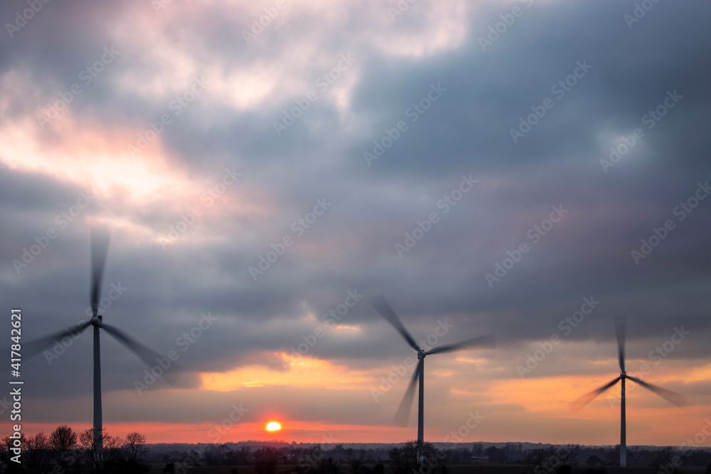 Obraz premium Three wind turbines with dramatic sunset sky