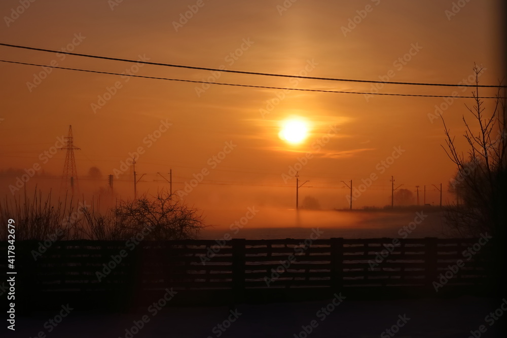 The sun rising over the railroad tracks with the disappearing fog, the Polish village of Morawica