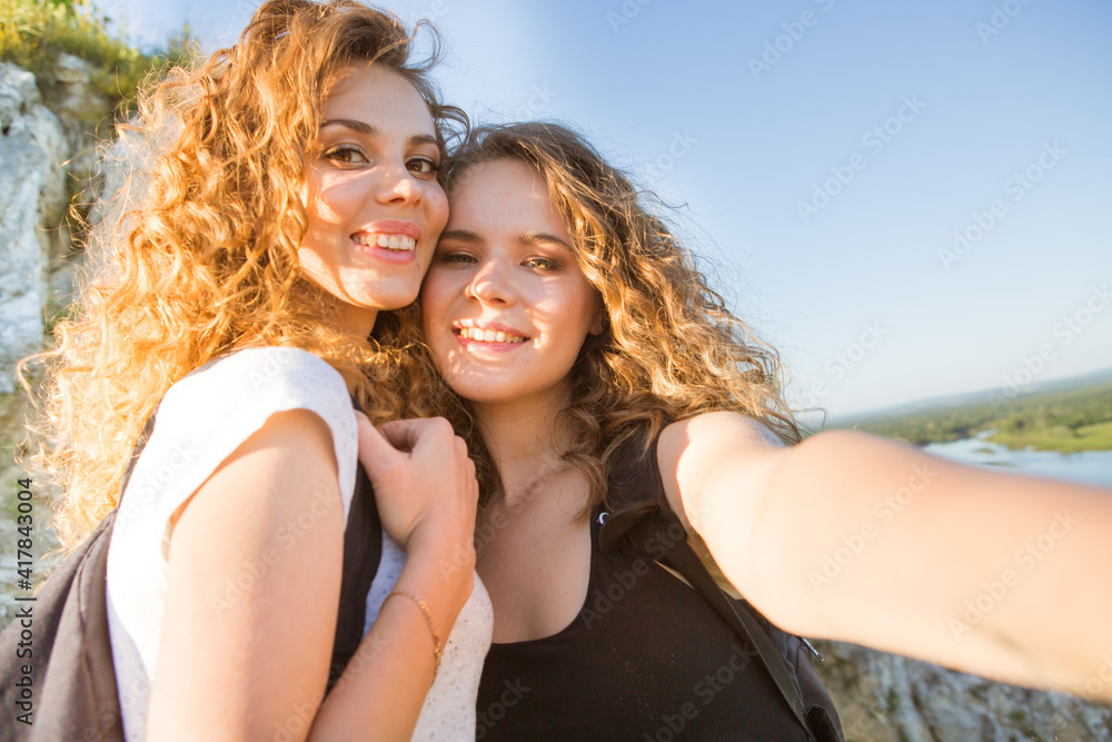 Two girls on a hike in the mountains take a selfie Two girls on a hike in the mountains take a selfie
