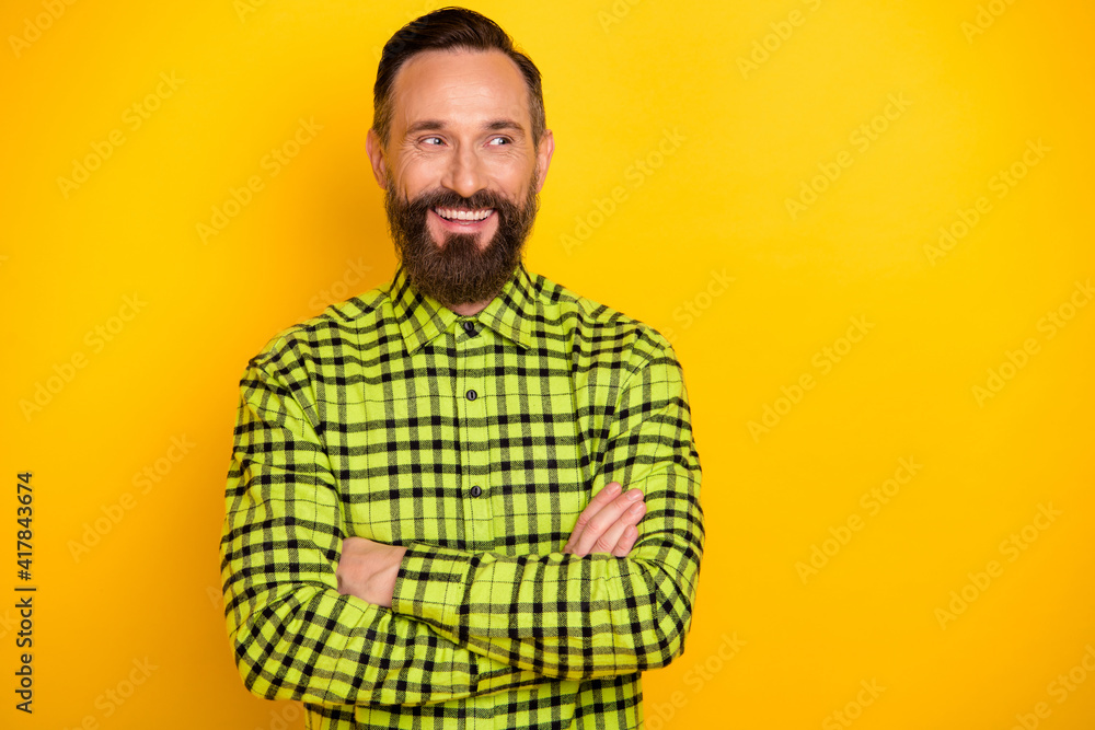Portrait of attractive cheerful man wearing checked shirt folded arms looking asside isolated over bright yellow color background