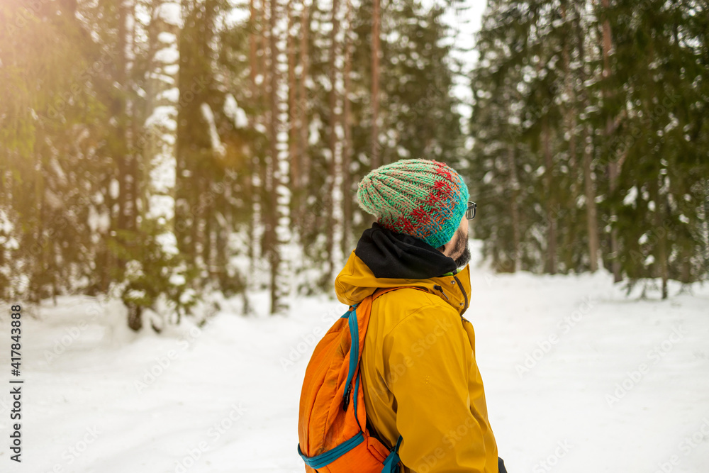 Rear view of man enjoying a walk through the woodland during winter
