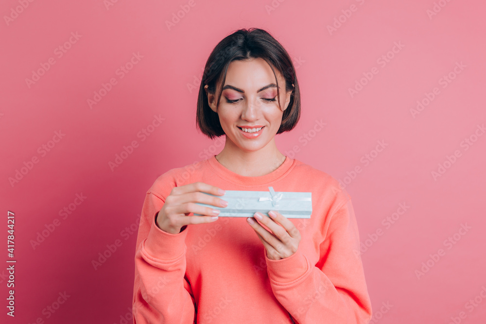 Portrait of happy smiling girl opening gift box isolated on pink background Portrait of happy smiling girl opening gift box isolated on pink background