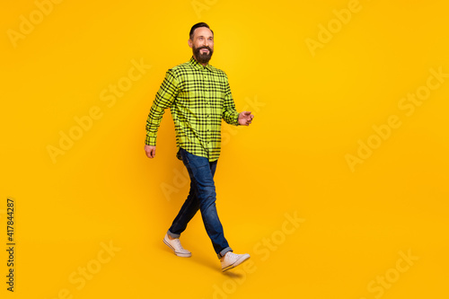Full body profile side photo of cheerful handsome man happy positive smile go walk step isolated over yellow color background