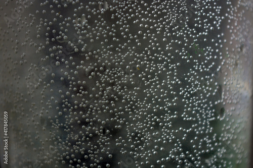 Dark unusual water with small white bubbles across the background. 