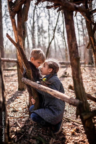 Young adventurers, boy and girl, building a wooden habitat in the wild forest during their social distant walking in lockdown time, walking on fresh air, outdoor active lifestyle