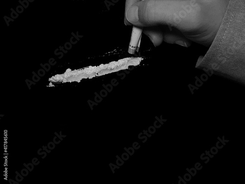 Businessman use 50 euro banknote to snorting cocaine drug powder line on black table