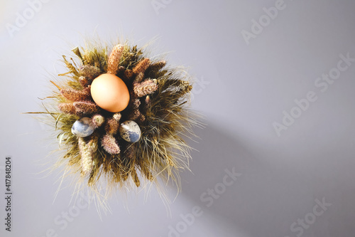 Easter eggs in a bouquet of dried flowers on a gray background. Close-up view from above. Background for your design or congratulations. Poster.