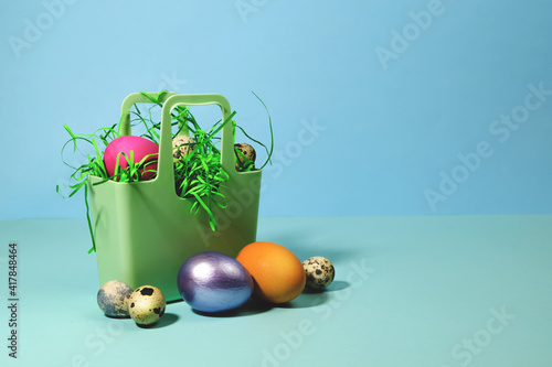 Easter eggs in a silicone basket on a blue background. Close-up side view. Congratulation postcard poster.