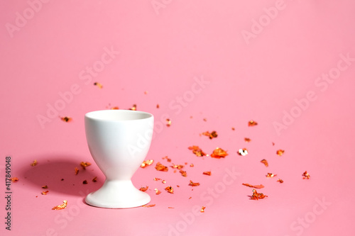 White egg stand on a pink background with blurred gold decor. The background is blurred. Place for your design or lettering.