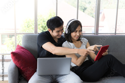 Asian teenager love couple using a tablet and computer in their living room