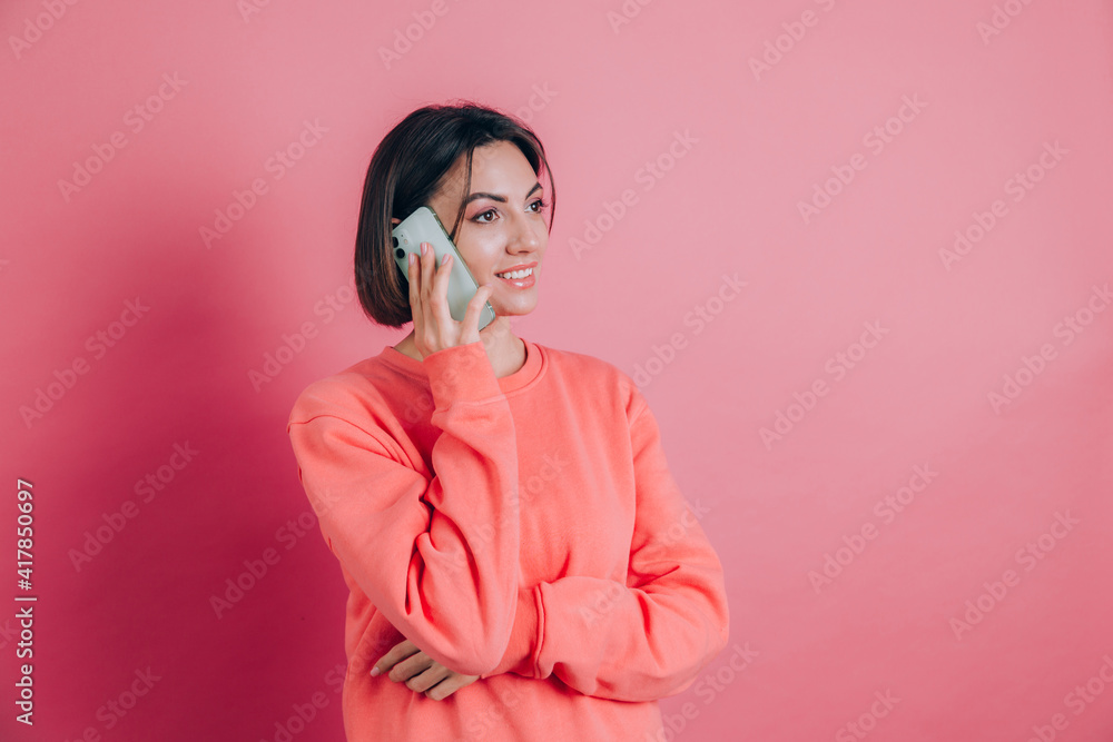 Photo of woman smiling while talking on smartphone isolated over pink background Photo of woman smiling while talking on smartphone isolated over pink background