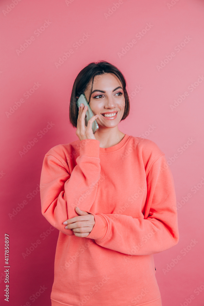 Photo of woman smiling while talking on smartphone isolated over pink background Photo of woman smiling while talking on smartphone isolated over pink background
