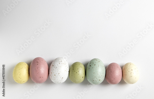 Speckled pastel easter eggs in a horizontal line on white background