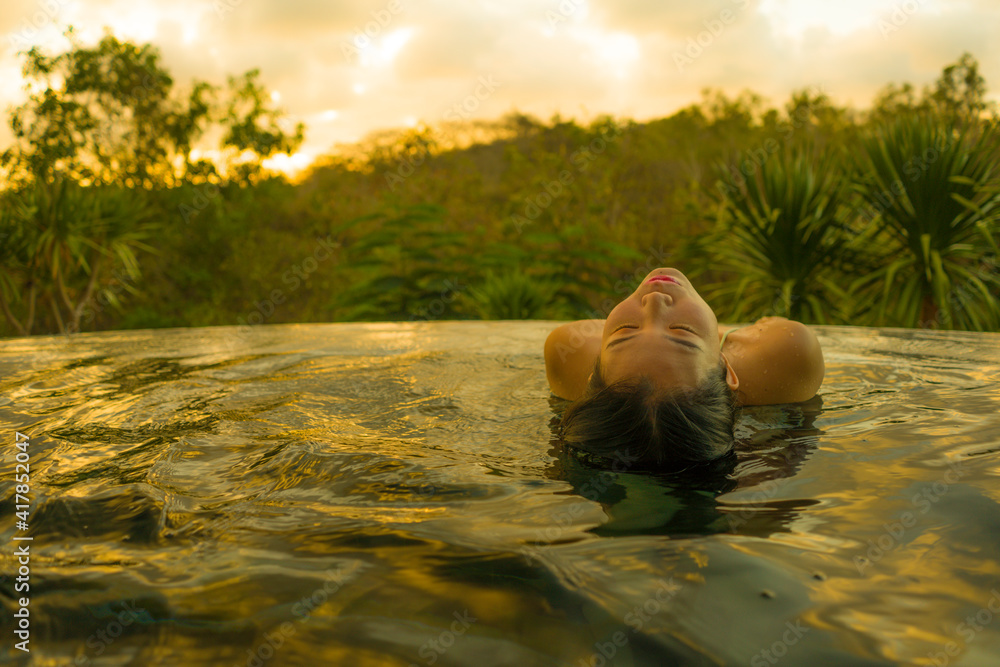 Fototapeta premium young woman relaxed at luxury resort infinity pool - happy and cheerful Asian Korean girl in bikini enjoying jungle view at hotel swimming pool during summer holidays travel