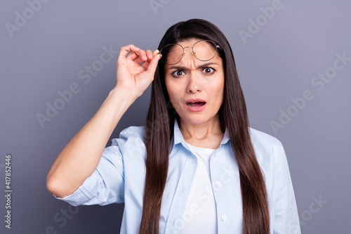 Photo of impressed shocked young lady dressed blue shirt arm glasses isolated grey color background