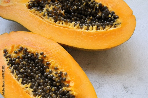 halved juicy papaya, two halves of papaya with seeds inside, orange fruit full of vitamins, healthy eating