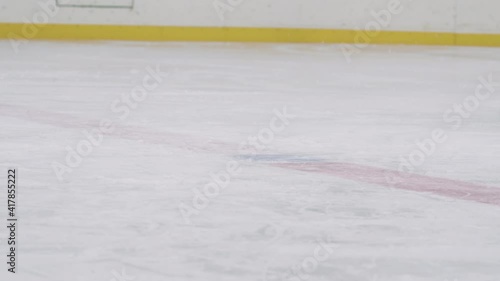 Slow-motion low-angle shot of unrecognizable hockey official dropping pluck while two opposing players trying to catch it with stick and win face-off