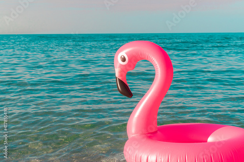 Sea background. Pink inflatable flamingo in blue ocean water for sea summer beach background. Luxury lifestyle travel. © Maksym