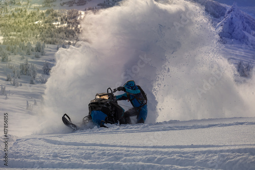 a guy on a mountain snowmobile skids and pushes full throttle, letting out large fountains of snow from under the tracks. bright skidoo motorbike and suit without brands. Winter fun. panoramic view
