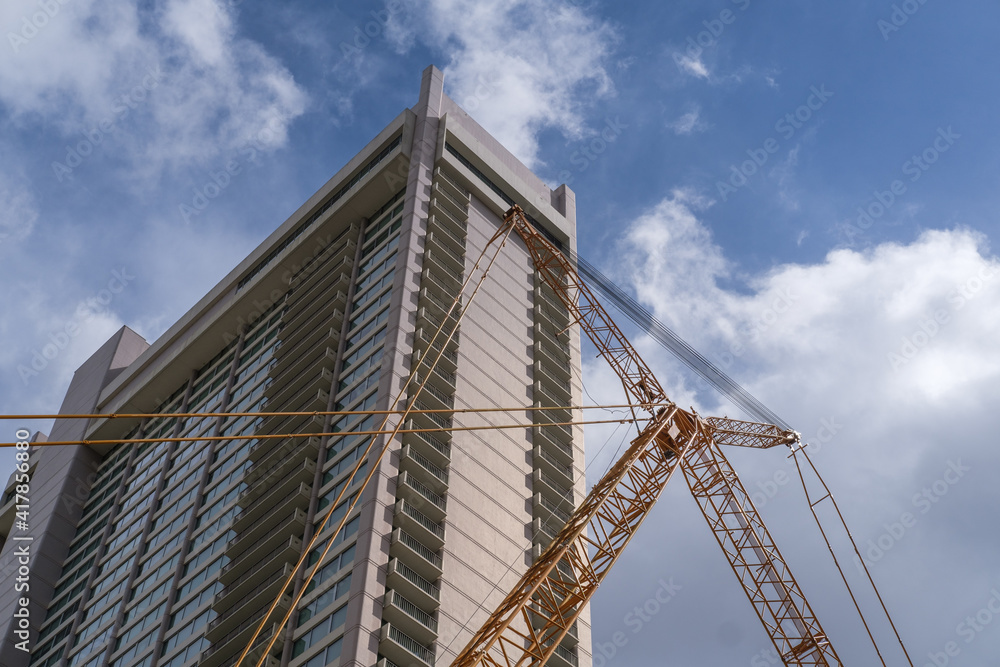 Tall building with crane in front and blue sky background