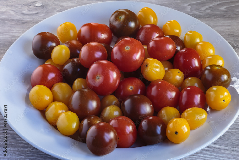 Multicolored tomatoes of different varieties in a dish. Fashionable vegan food. Multicolored tomatoes of different varieties in a dish. Fashionable vegan food.