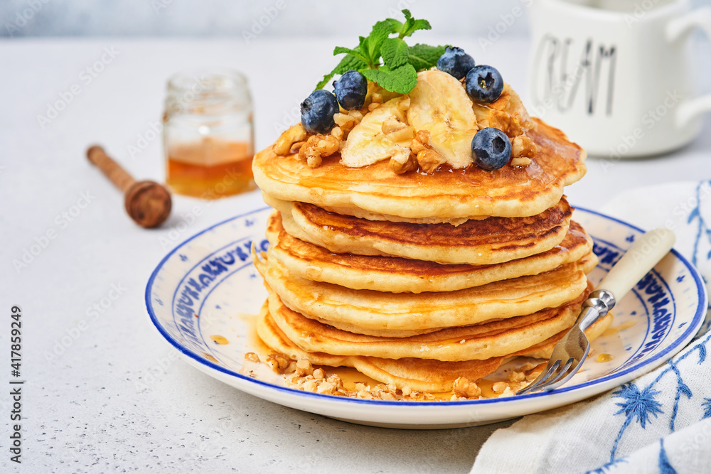 Pancakes with banana, walnut, honey and caramel for a breakfast. Selective focus