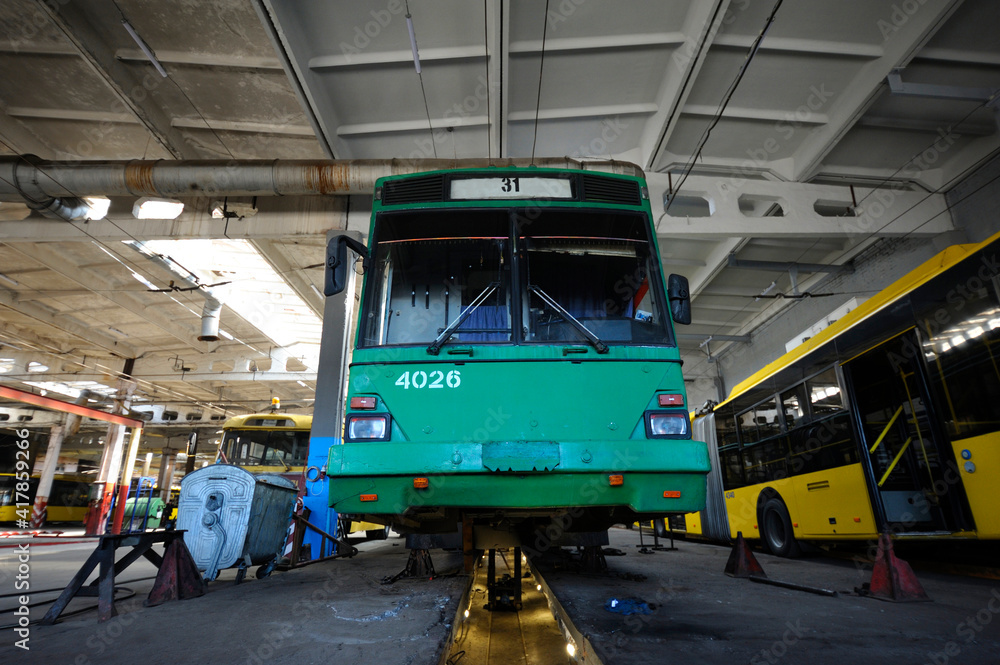 An old but still in use trolleybuses parked on the inspection pit at the trolley depot. Hangar of depot maintenance