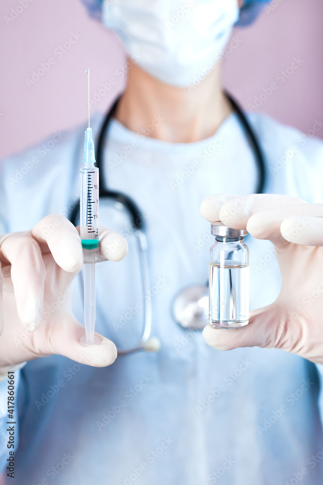 Fototapeta premium Doctor or nurse in medical mask and in protective gloves holds syringe and medical injection in hands. Influenza and coronavirus vaccination. Close-up.