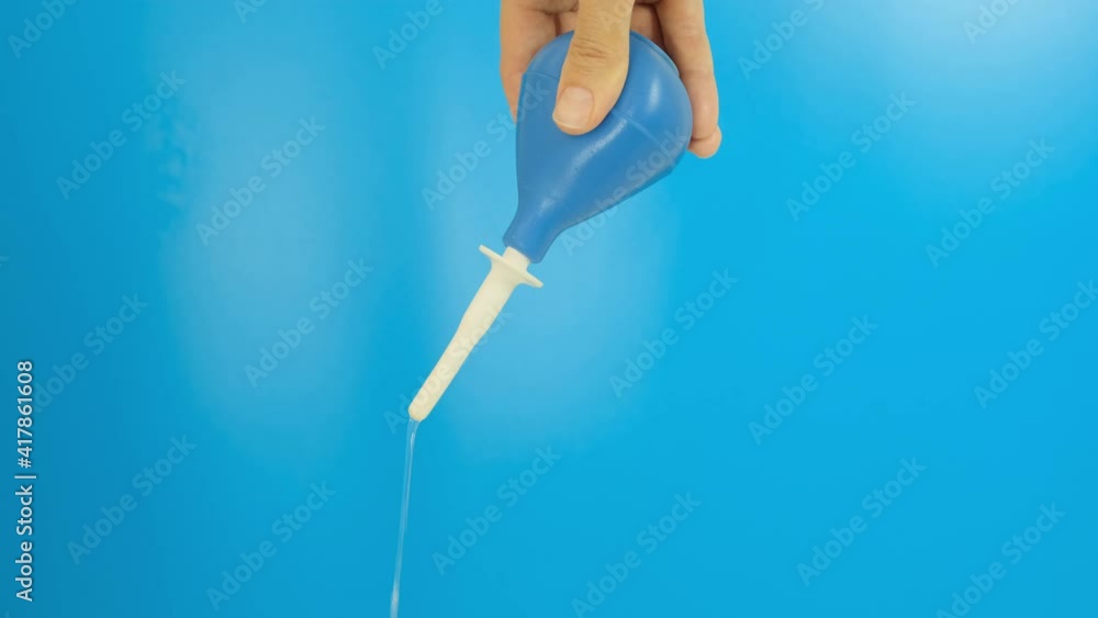 Hand with a blue enema puming, compressing, squeezing and injecting water on a blue background