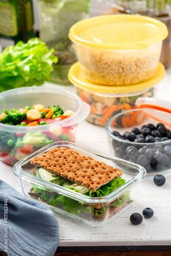 Various food in plastic and glass containers. Salad, bulgur, sandwiches and berries in plastic containers on a white background. Food storage, takeaway