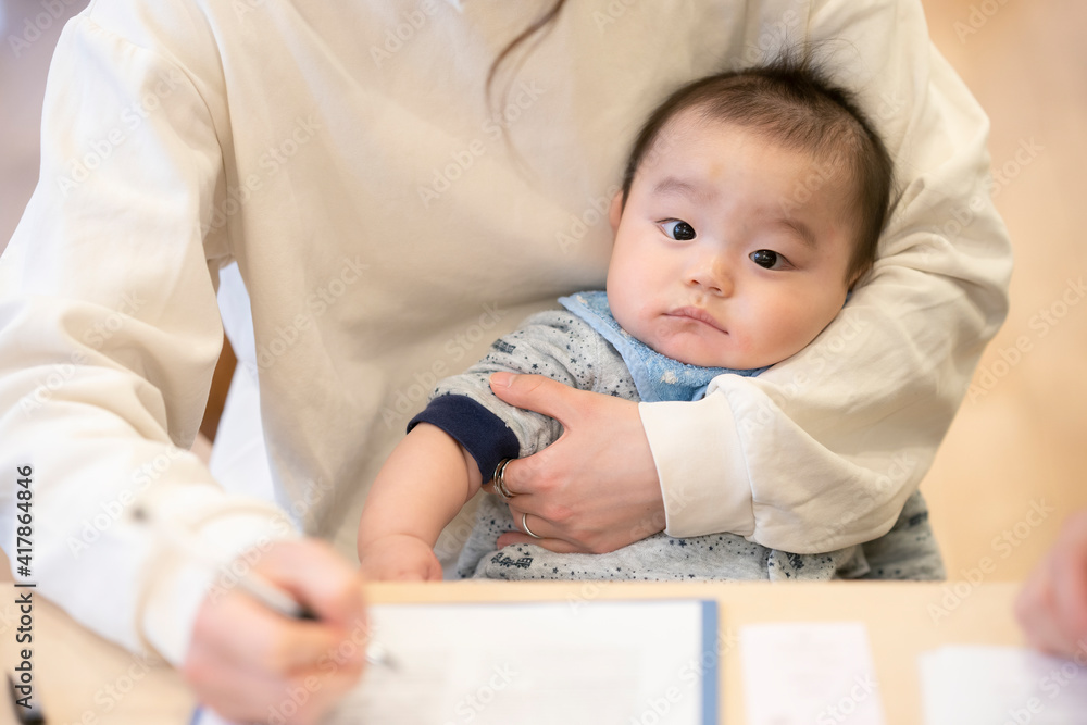 デスクワークをするお母さんに抱かれる赤ちゃん デスクワークをするお母さんに抱かれる赤ちゃん
