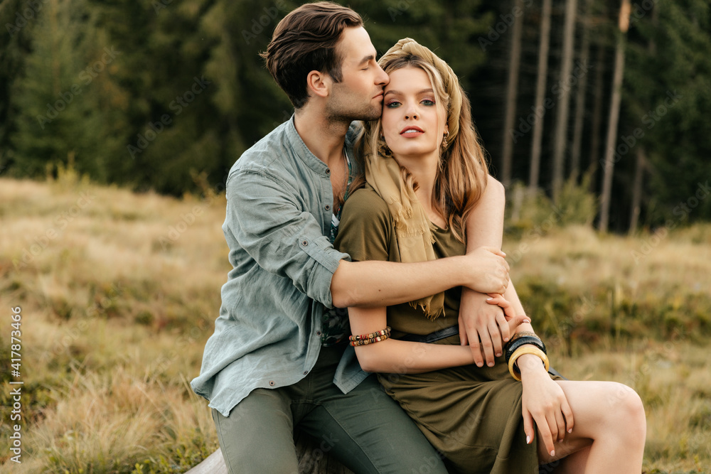 Loving young couple hugging together in nature on the background of mountains Loving young couple hugging together in nature on the background of mountains