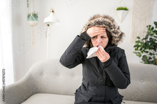 Woman With Warm Clothing Feeling The Cold Inside House on the sofa she having flu and using tissue