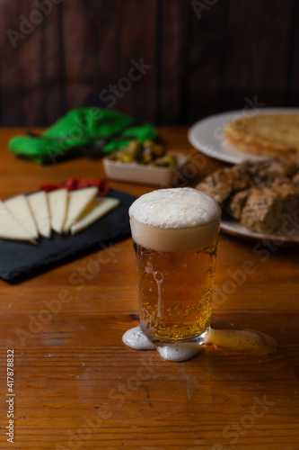 Delicious beer glass freshly poored with foam on a tapas bar background. photo