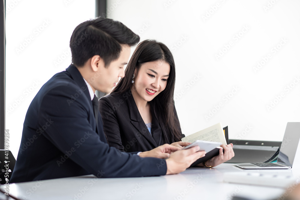 Image of businessman and businesswoman meeting and analyzing work using a tablet office taking note . Image of businessman and businesswoman meeting and analyzing work using a tablet office taking note .