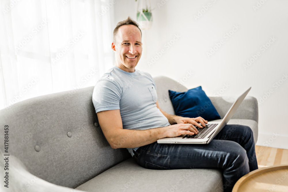 man watching and working on computer laptop at home