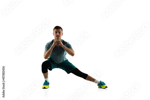 Squats. Young caucasian male model in action, motion isolated on white background with copyspace. Concept of sport, movement, energy and dynamic, healthy lifestyle. Training, practicing. Authentic.