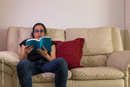 a girl sitting enjoying a book on a sofa