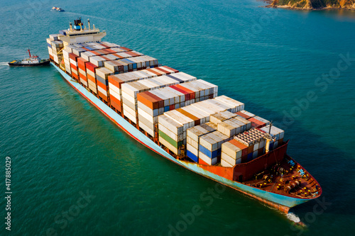 large container ship and tug boat sailing on the green sea