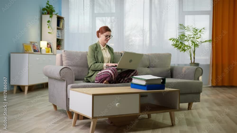 freelancer, young woman in jacket and pajama pants with laptop works at home during quarantine and self-isolation freelancer, young woman in jacket and pajama pants with laptop works at home during quarantine and self-isolation