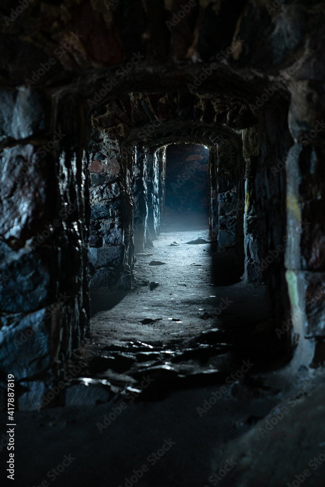 A dark, damp, cold dungeon corridor with stone walls all along the hallway