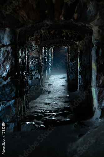 A dark, damp, cold dungeon corridor with stone walls all along the hallway © KAPhotography