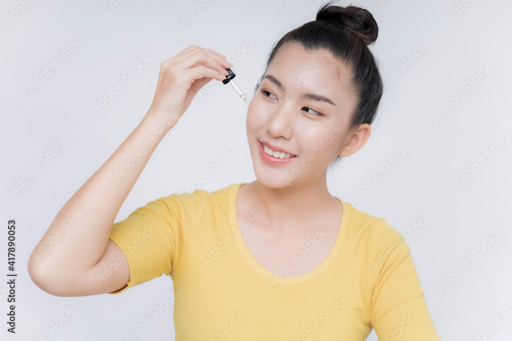 Beautiful Asian woman applying anti aging moisturizing serum on her face