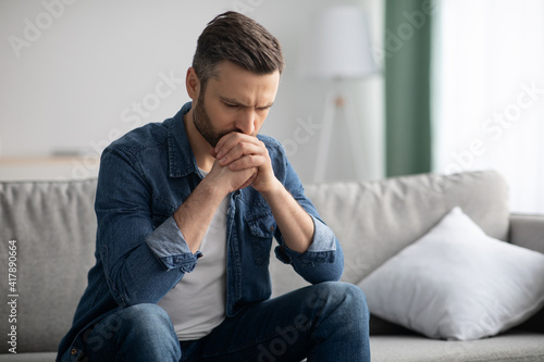 Obraz na plátně Upset bearded man sitting on sofa in living room