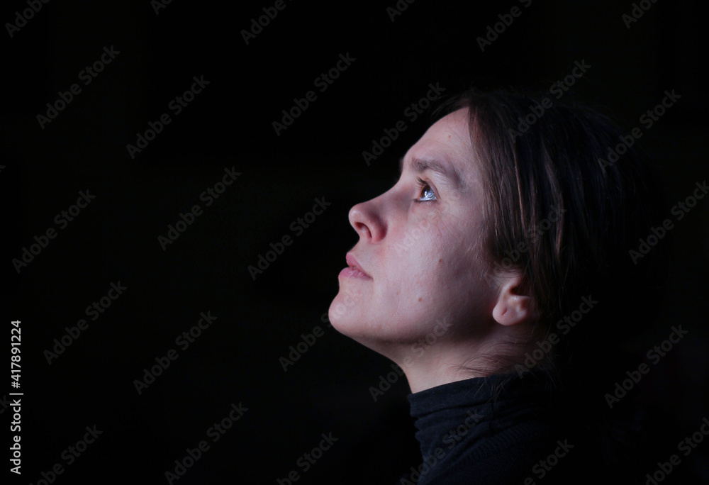 Profile portrait of a girl, with an antique appearance, no makeup, with her head raised to the sky, looking up, surrounded by a black background Profile portrait of a girl, with an antique appearance, no makeup, with her head raised to the sky, looking up, surrounded by a black background