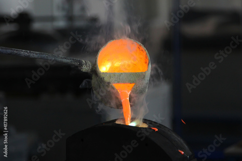Pouring molten metal at the factory. Metallurgy concept, metal smelting. Being poured from the crucible into the mold. photo